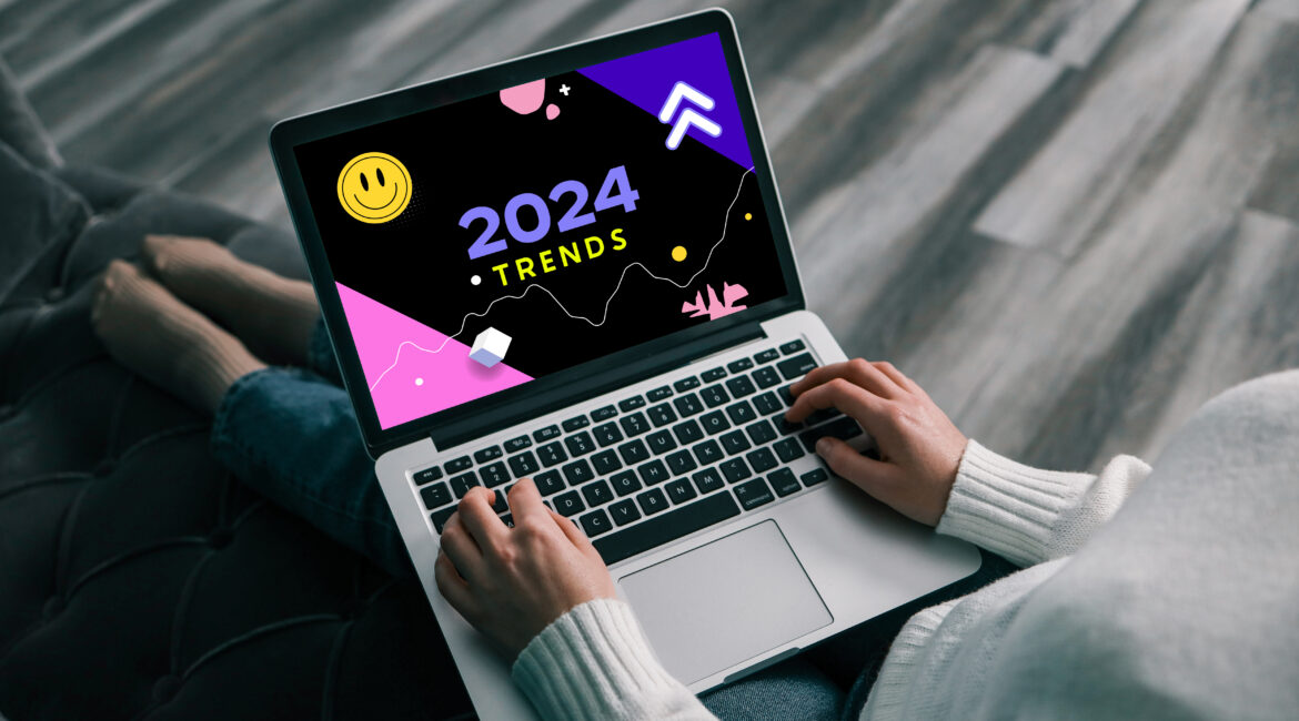 Person typing on a laptop displaying a screen with colorful graphics and the text '2024 Trends'.