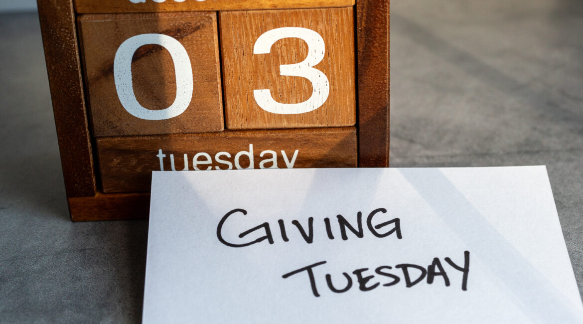 A wooden calendar displaying "December 03, Tuesday" next to a card with the handwritten text "Giving Tuesday.