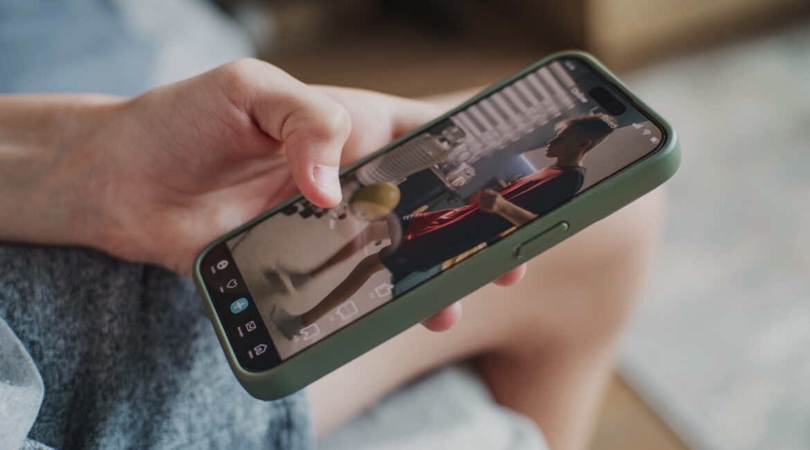 A close-up of a person holding a smartphone, watching a short-form video in portrait mode.